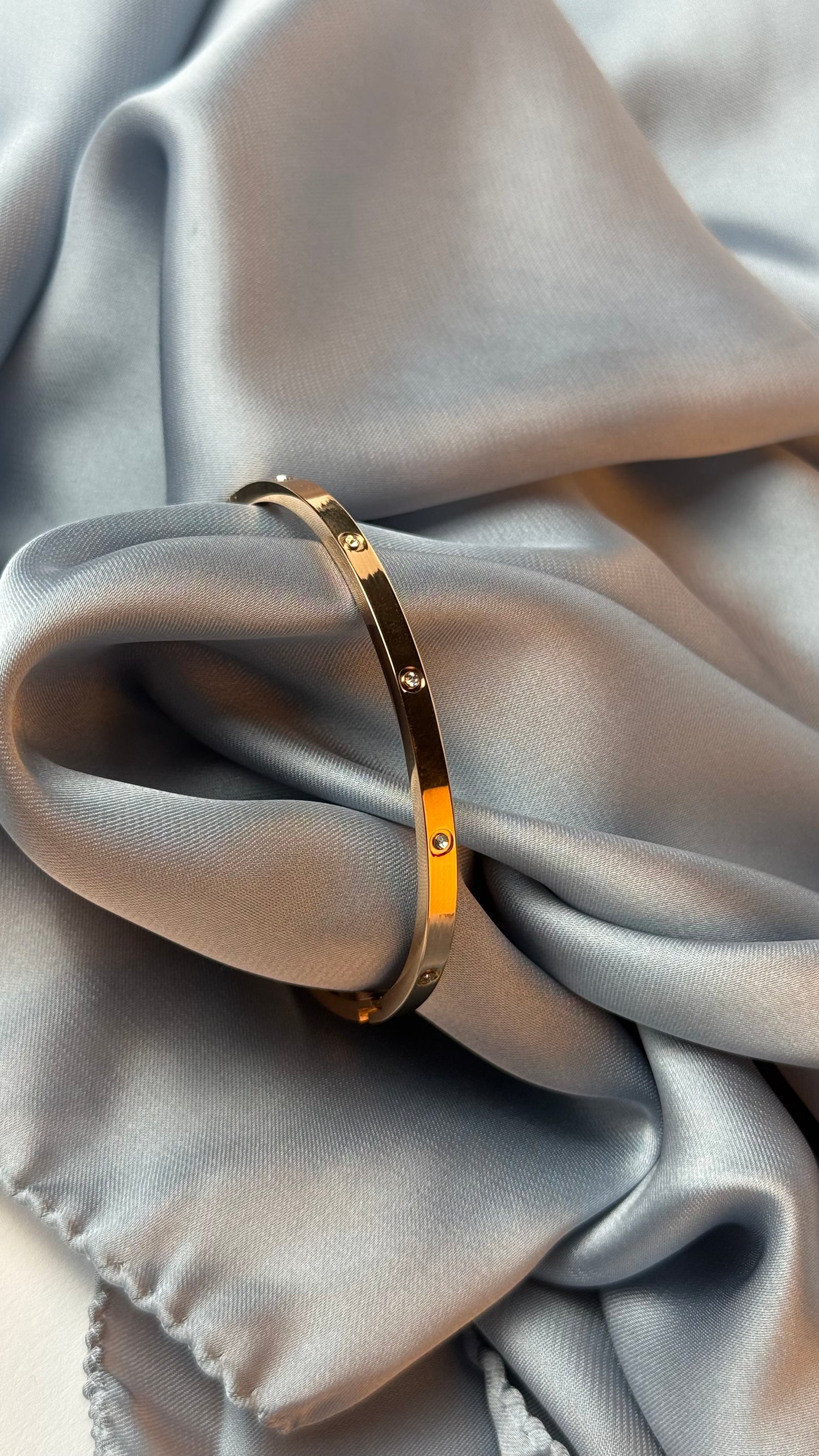 Gold bracelet on a soft gray fabric background