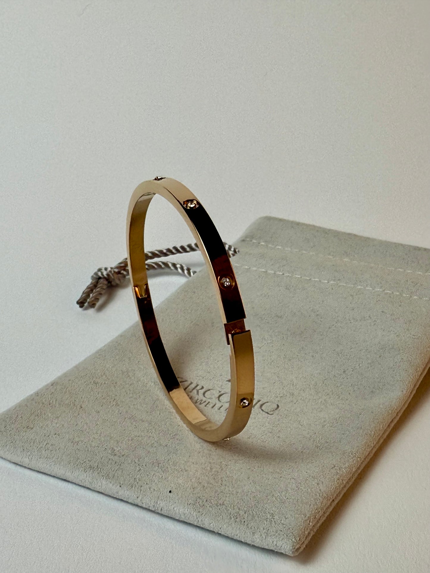 Gold bracelet on a branded jewelry pouch with a plain background