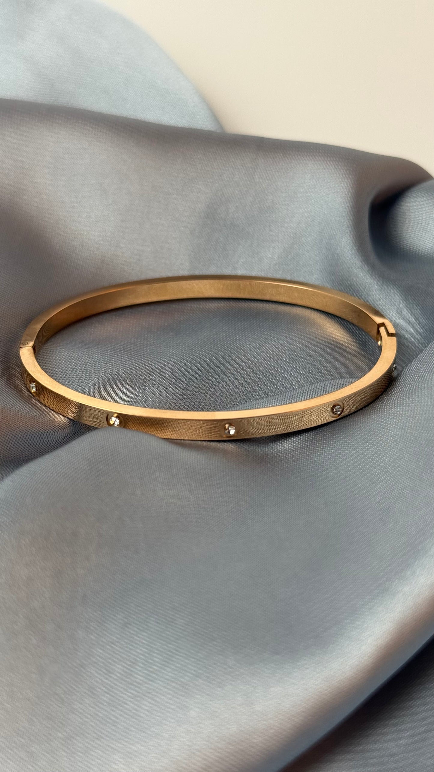 Gold bracelet on a gray fabric surface