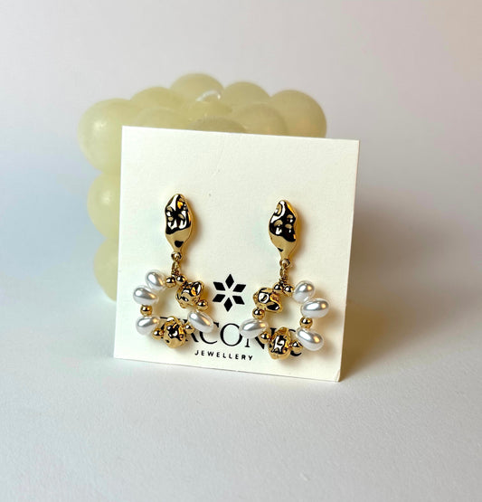 Pair of gold and pearl earrings on a display card with a visible brand logo.
