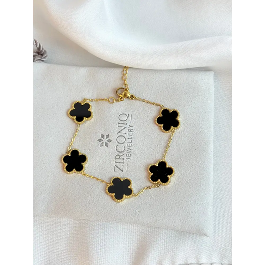 Gold bracelet with black flower-shaped charms on a Zirconiq Jewellery branded card.