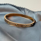 Gold bracelet with small stones on a light blue fabric background