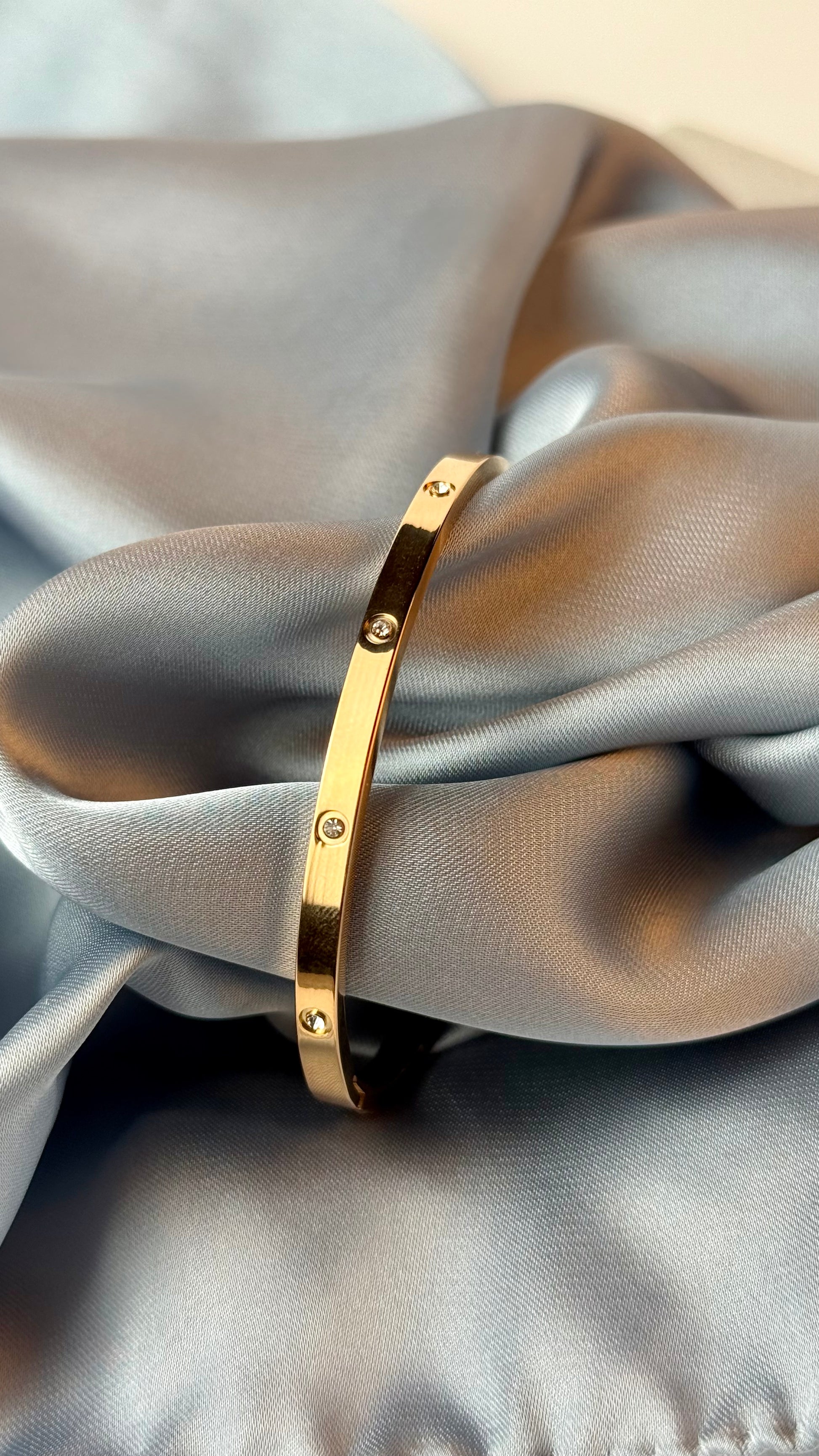 Gold bracelet on a gray fabric background