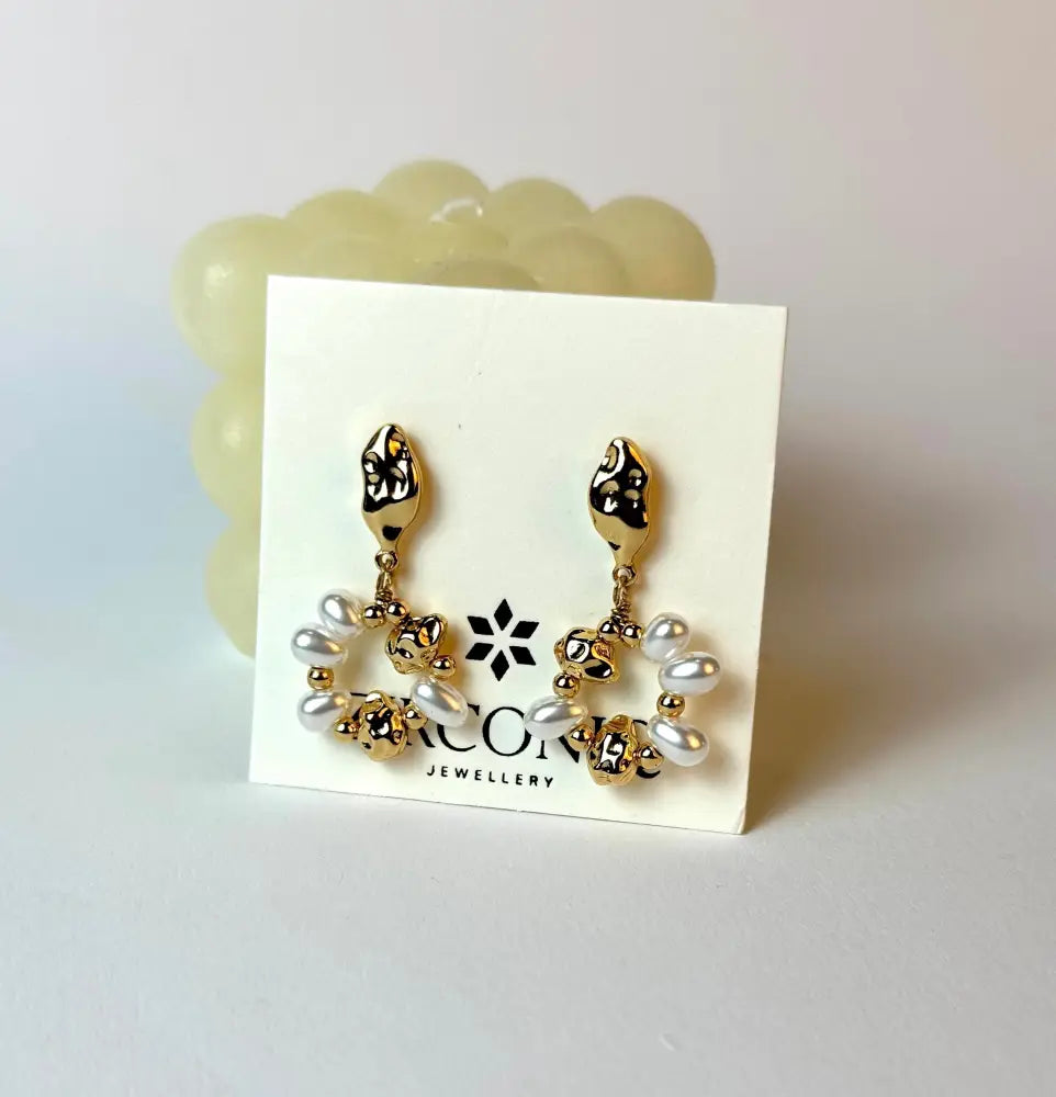 Pair of gold and pearl earrings on a display card with a visible brand logo.