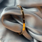 Gold bracelet on a gray fabric surface