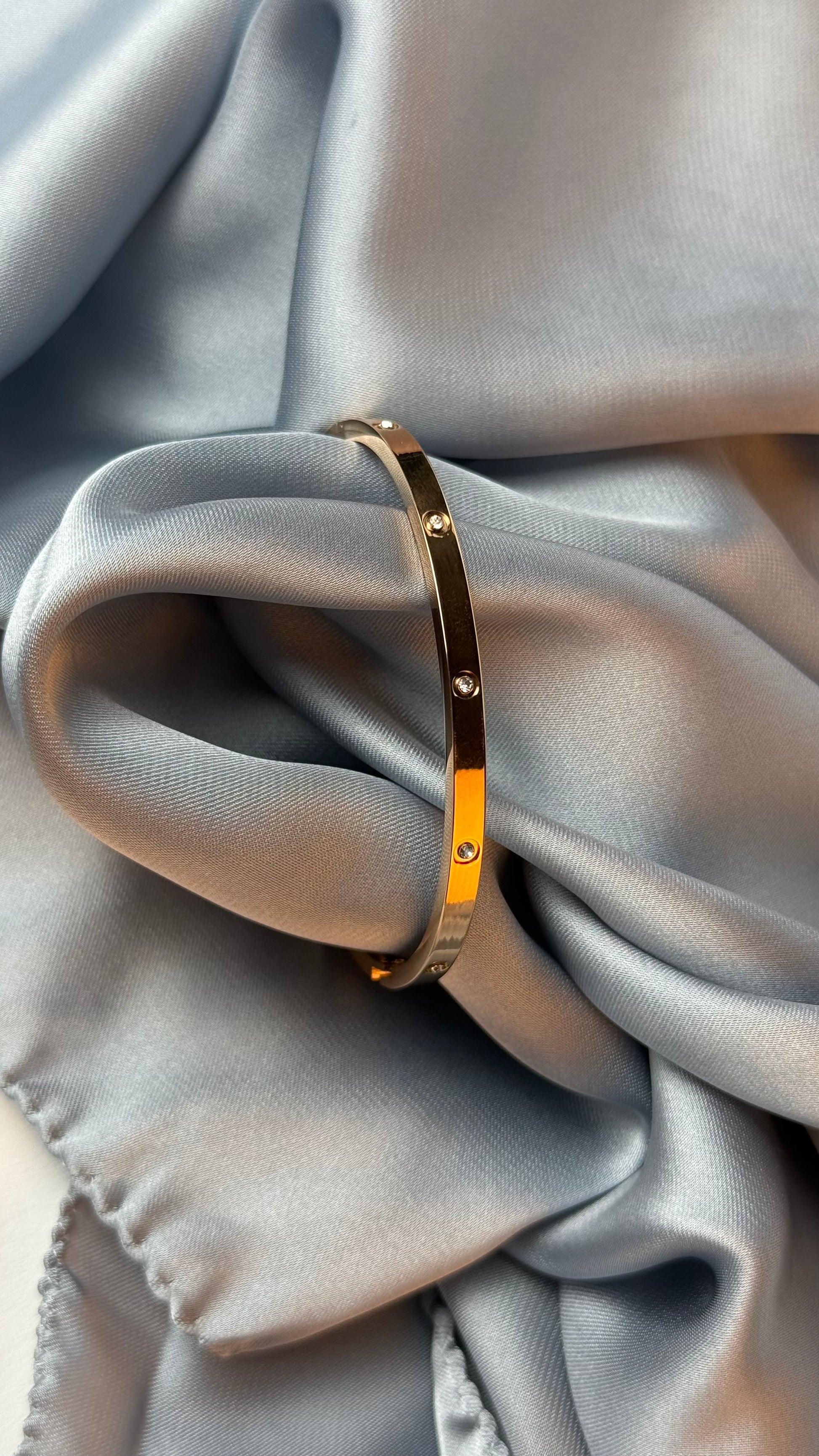Gold bracelet on a gray fabric surface