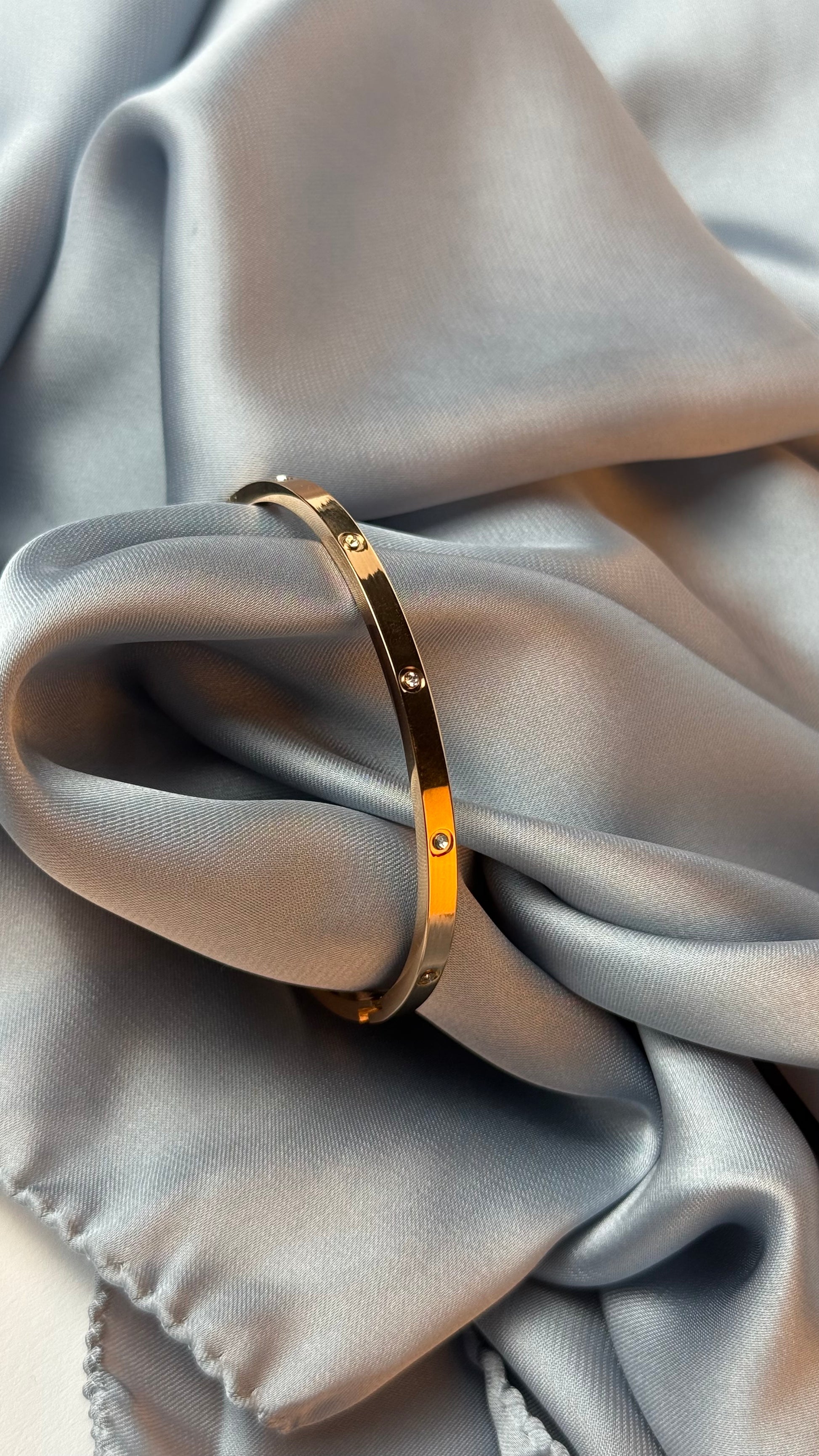 Gold bracelet on a soft gray fabric background