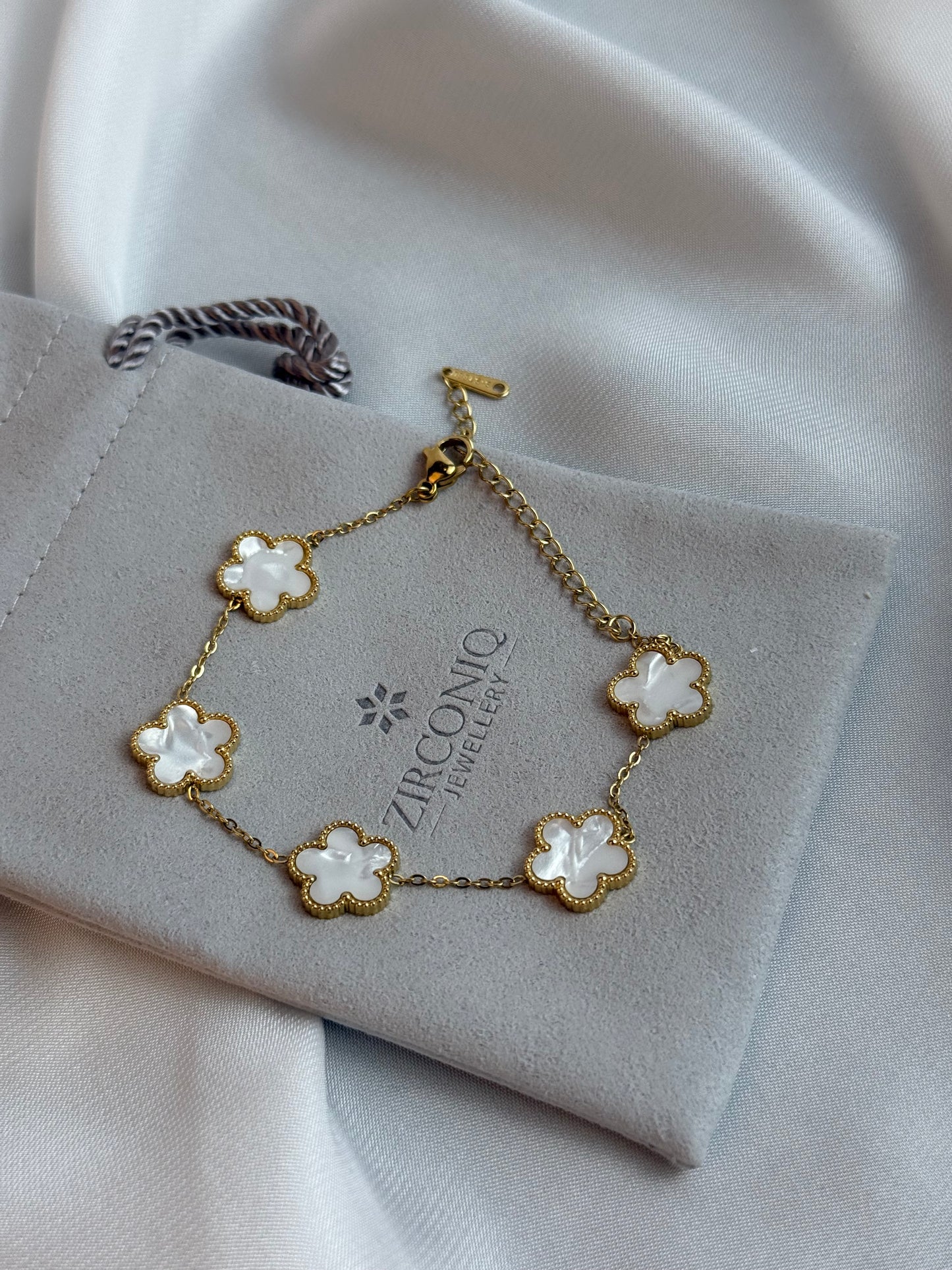 Gold bracelet with floral designs on a gray jewelry box