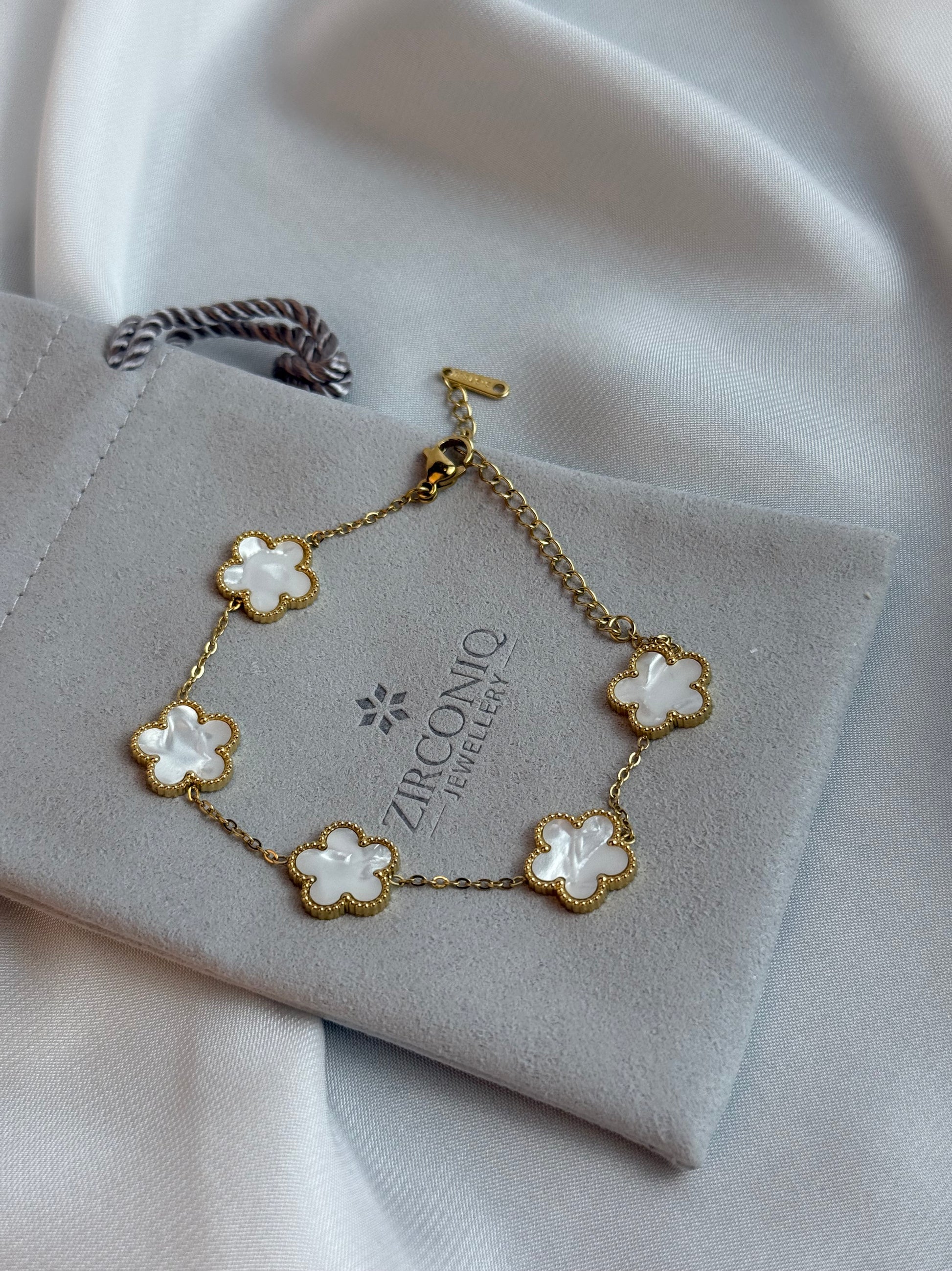Gold bracelet with floral designs on a gray jewelry box