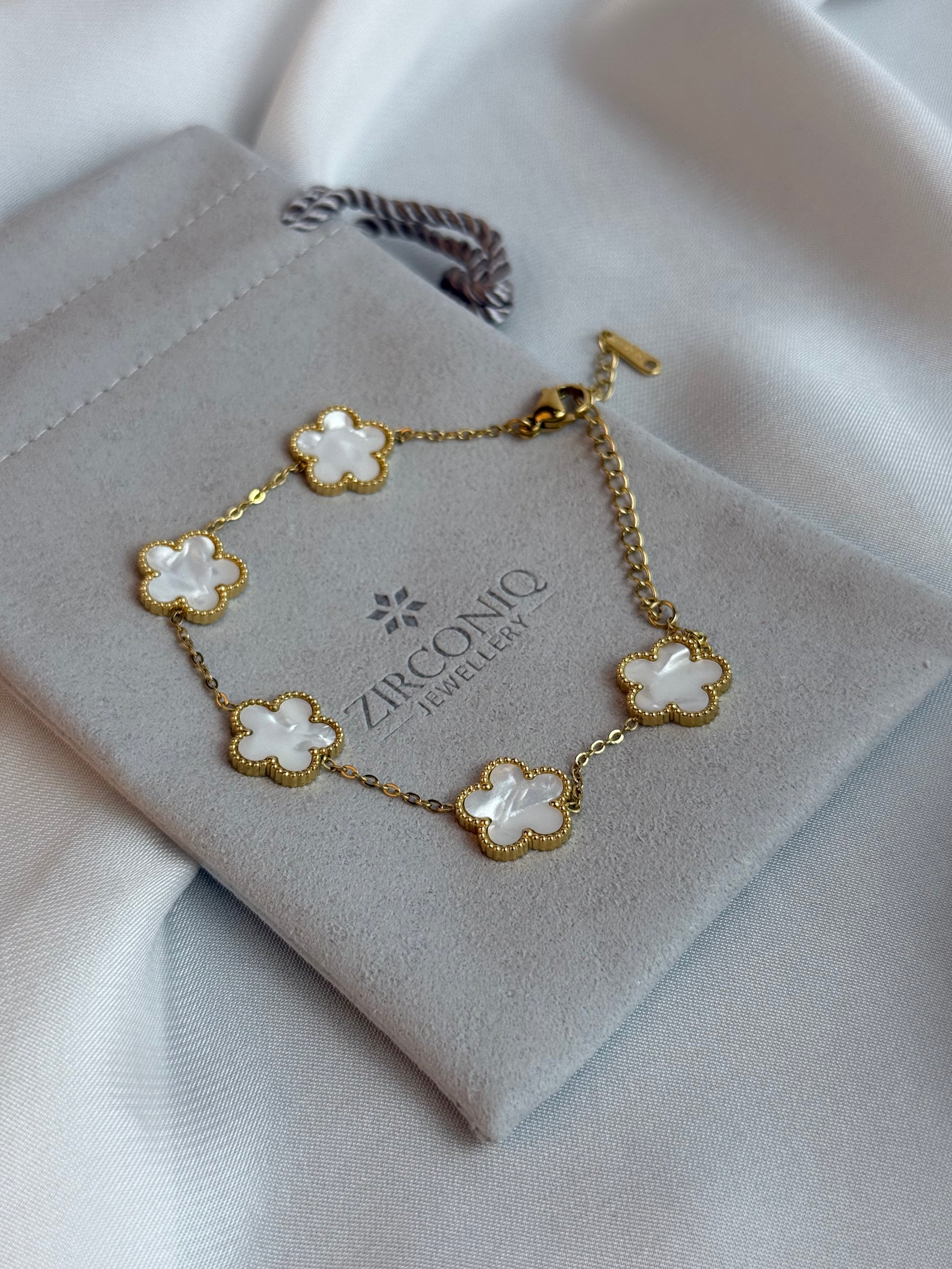 Gold bracelet with floral designs on a branded box