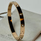 Gold bracelet with gemstones on a light gray surface