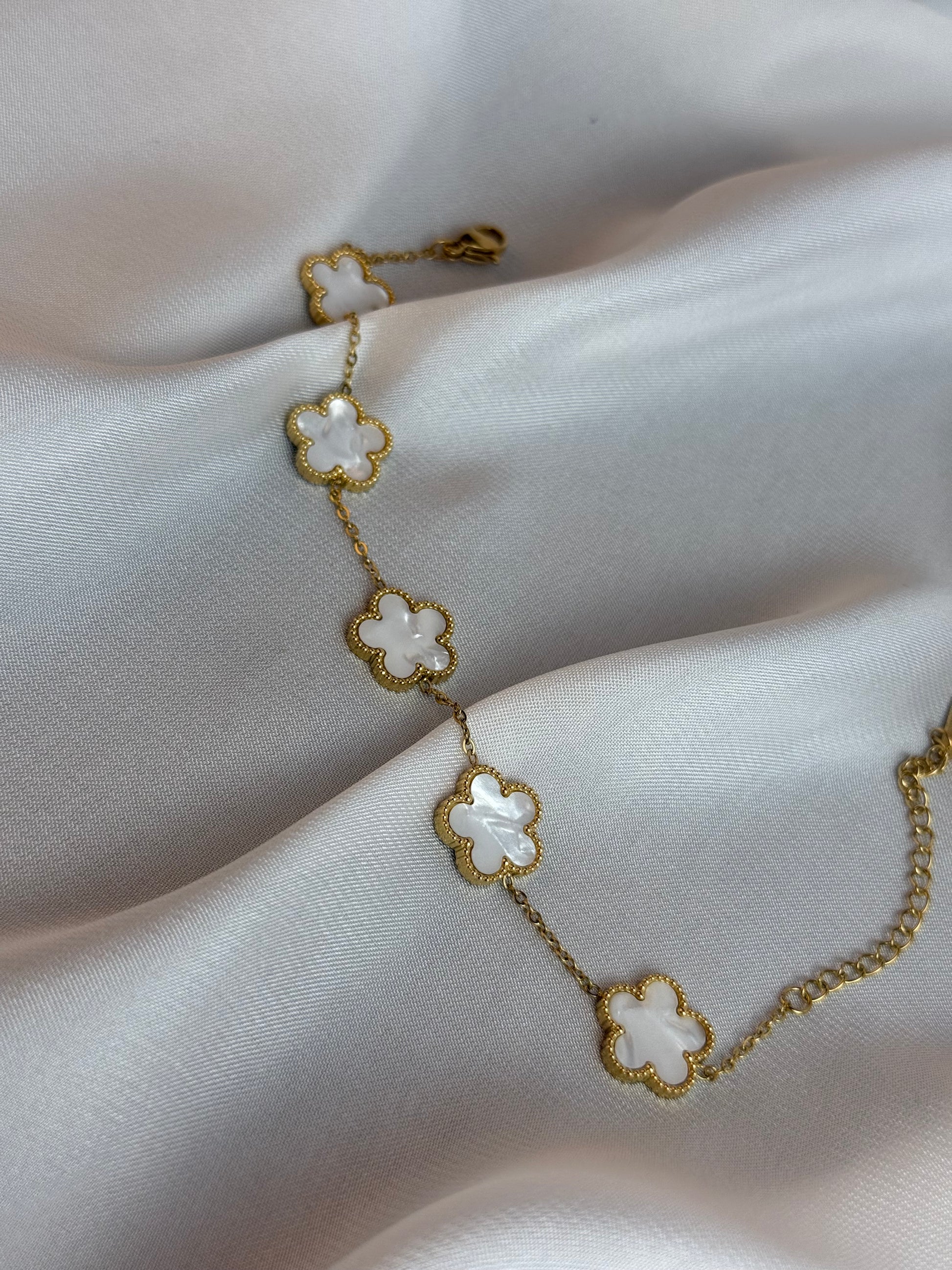 Gold bracelet with floral designs on a white fabric background