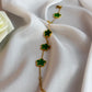 Gold bracelet with green clover charms on a white fabric background