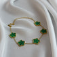 Gold necklace with green clover-shaped pendants on a white fabric background