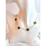 Gold necklace with green clover-shaped pendants on a white cushion