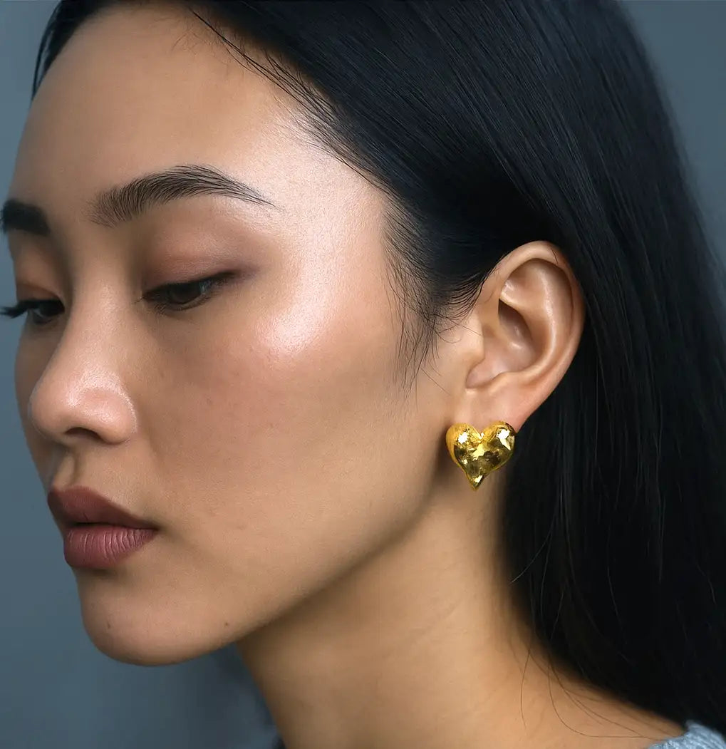 Gold heart-shaped stud earring with a textured, faceted surface.