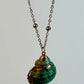Necklace with a green shell pendant on a light gray background