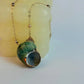 Necklace with a green and gray pendant on a white background