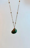 Necklace with a green shell pendant on a light gray background