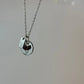 Silver necklace with a round pendant on a light gray background