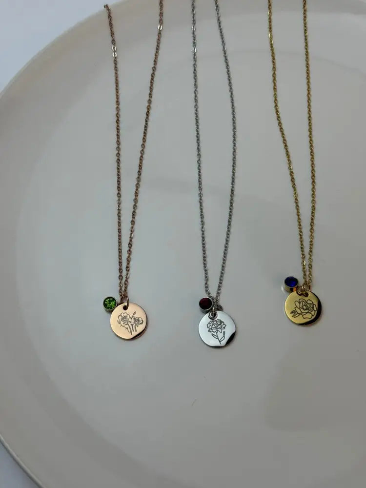 Three necklaces with circular pendants on a white plate