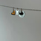 Necklace with heart, letter 'V', and circular charm on a plain background