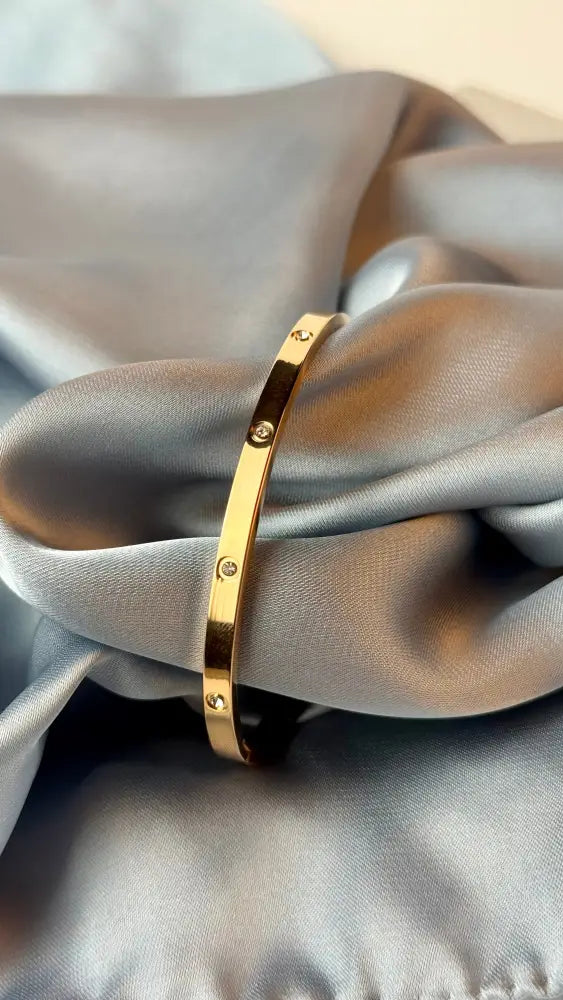 Gold bracelet on a gray fabric background