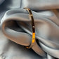 Gold bracelet on a gray fabric surface
