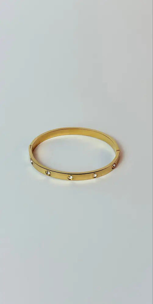 Gold ring with small stones on a light gray background